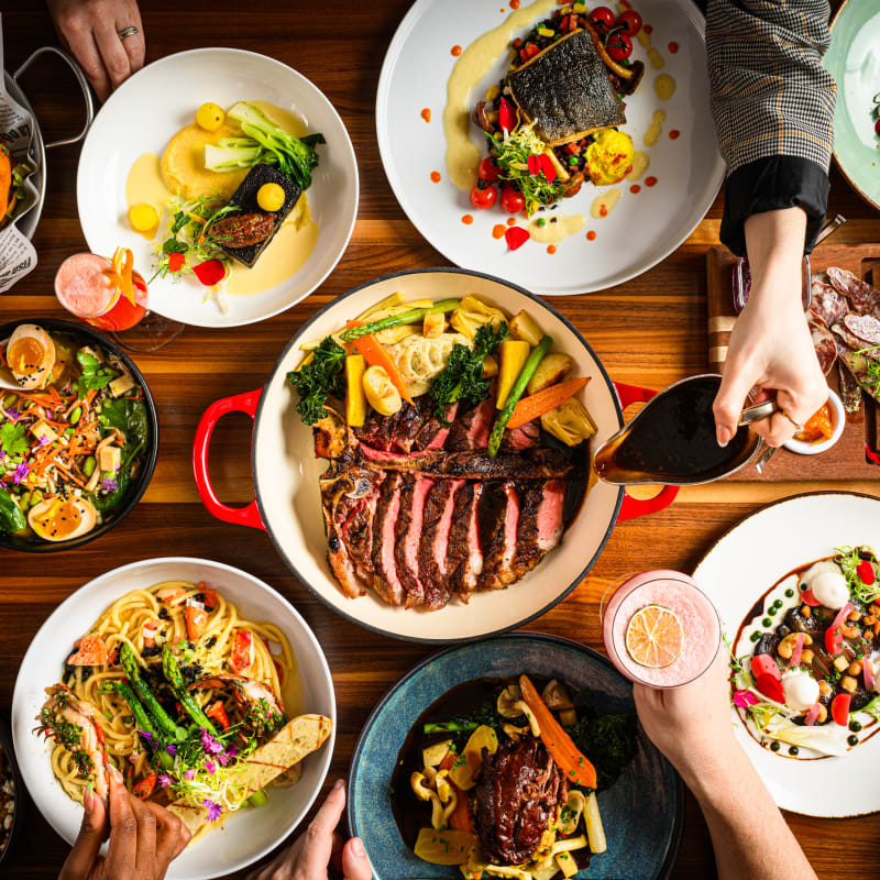 Grande table remplie de plats variés colorés et gastronomiques, vue du dessus.