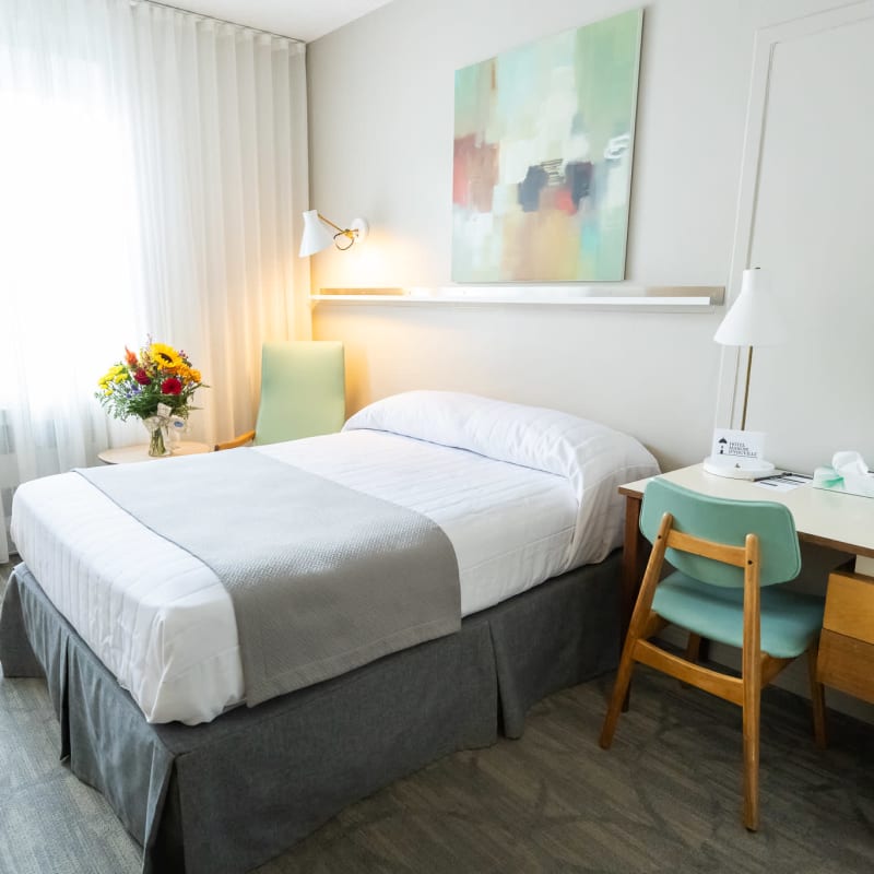 Bright guest room at Hôtel Manoir d’Youville with a bed and work desk.