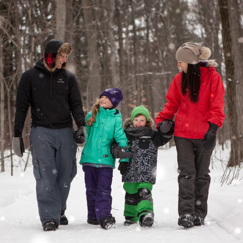 Famille marchant dans un sentier enneigé en forêt.
