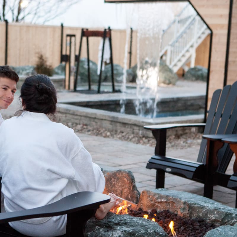 2 personnes relaxant près d'un feu à l'extérieur au spa. 