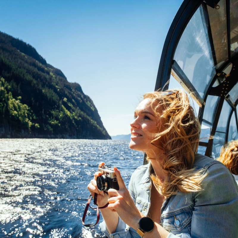 Les navettes maritimes du Fjord - Une femme sur un bateau tient une caméra.