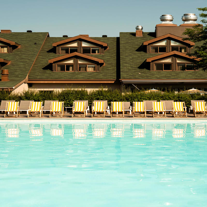 Chaises longues et parasols au bord de la piscine au Sun Club du Manoir Saint-Sauveur.