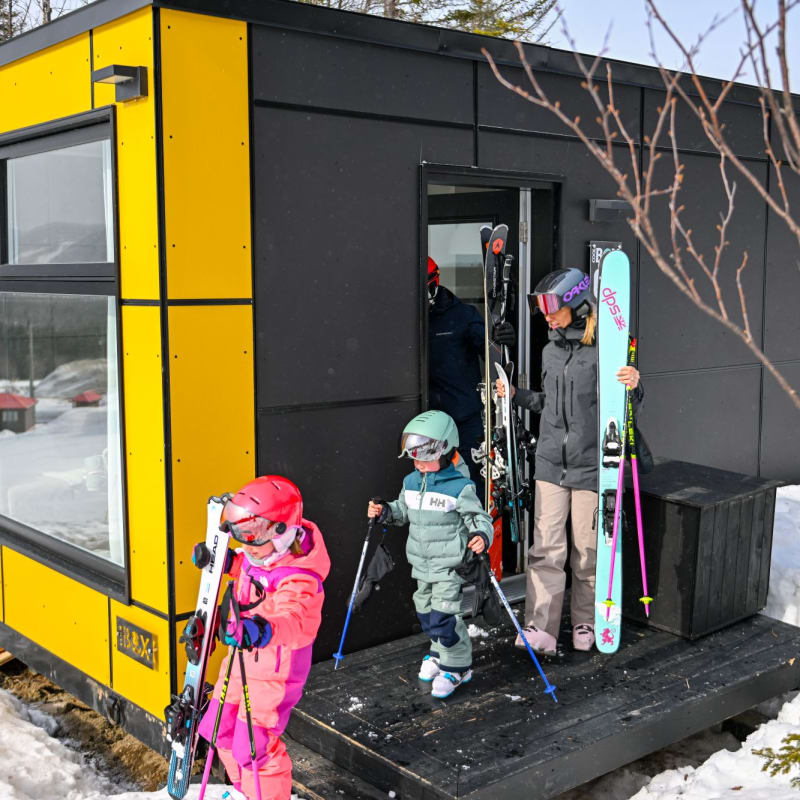 Famille à l'extérieur d'un hébergement Coolbox au Mont Grand-Fonds.