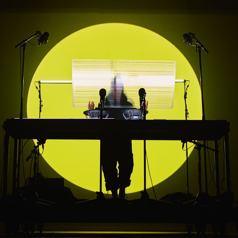 A DJ on stage, behind his turntable, with a round, sun-yellow backlight at the MUTEK festival