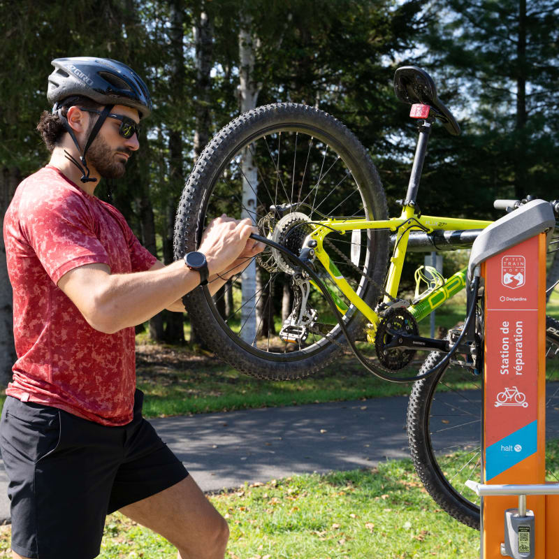 Cyclistes qui répare son vélo sur le parc linéaire du P'tit train du Nord.