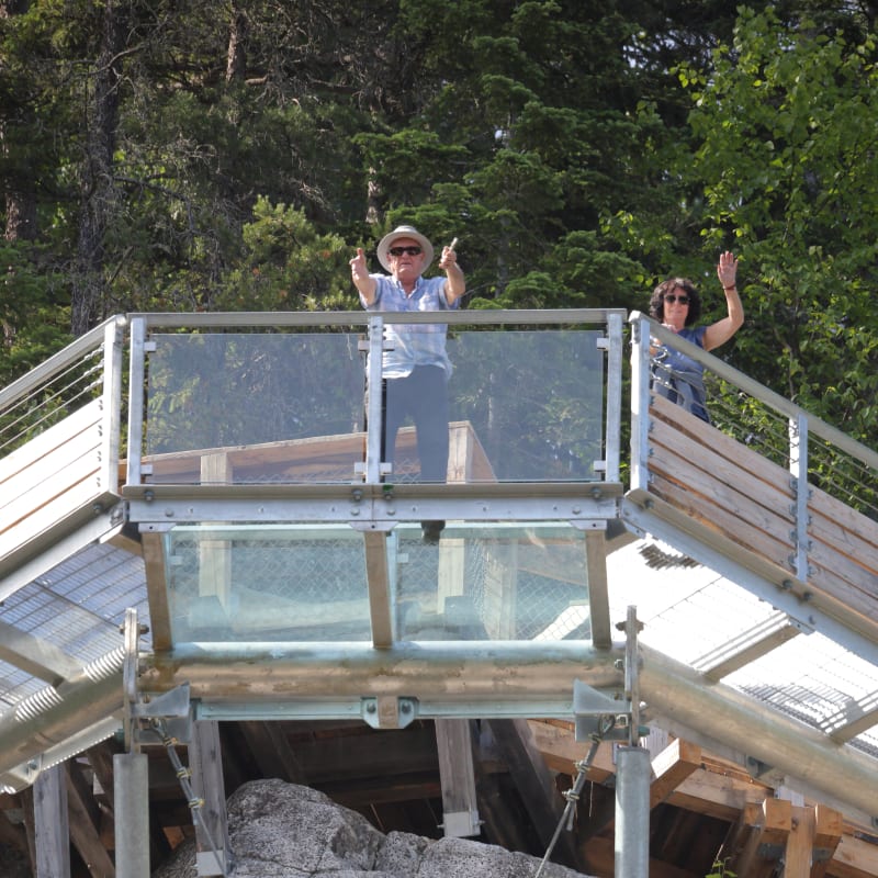 Deux visiteurs sur le plancher de verre au Parc le Trou de la Fée