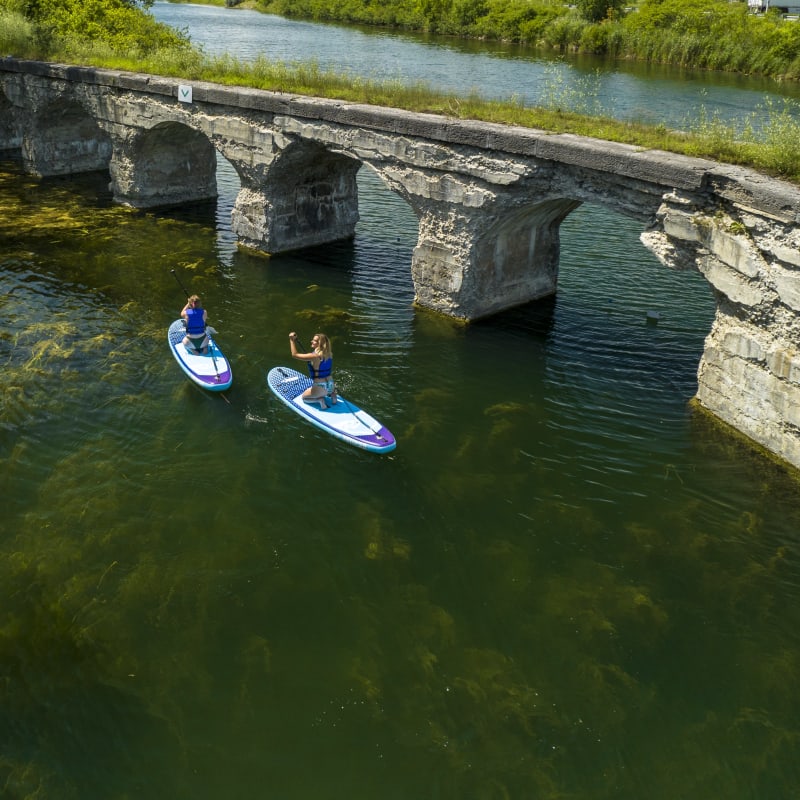 Deux personnes font de la planche à pagaie au Parc régional du canal de Soulanges.