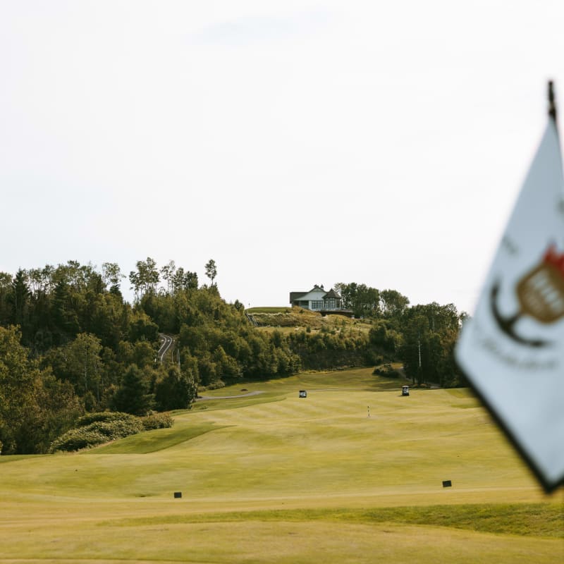 Vue rapprochée d'un drapeau, avec une parcours de golf en arrière-plan.
