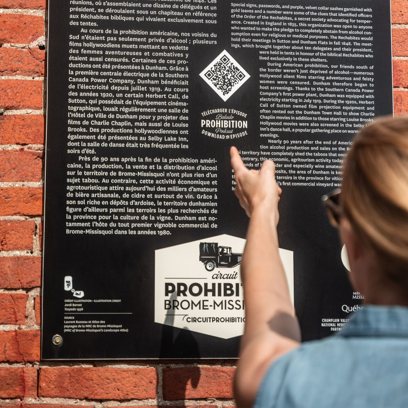 Femme qui lit un panneau sur la route de la Prohibition dans Brome-Missisquoi.