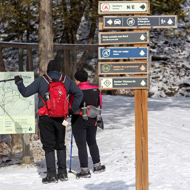Un homme et une femme en randonnée pédestre l'hiver dans le parc de la Gorge de Coaticook.