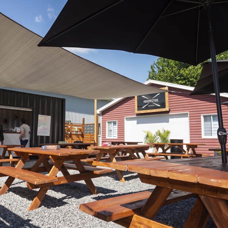 Terrasse de la microbrasserie Perspective, avec tables à pique-nique et parasols.