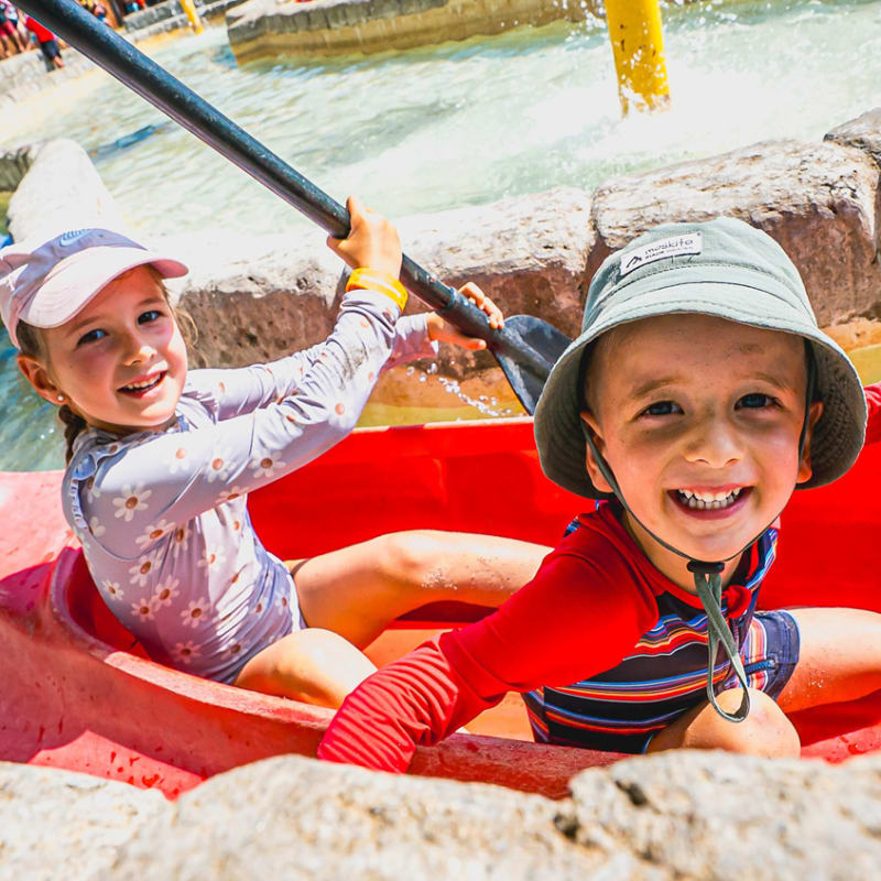 Deux jeunes enfants dans un petit kayak dans un circuit d'eau calme