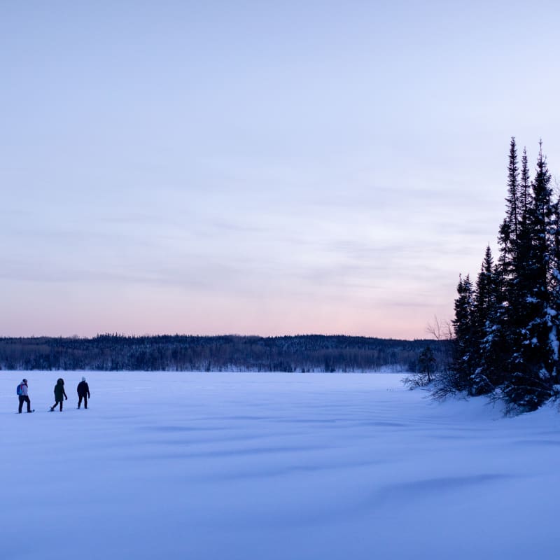 Corporation Nibiischii - Trois personnes au coeur d'un paysage enneigé