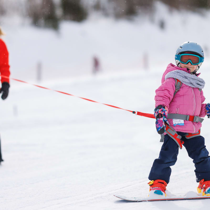 Jeune fille en train d'apprendre la planche à neige avec une monitrice.