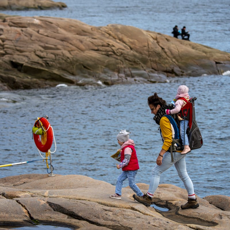 Mother and two kids walking by the sea.