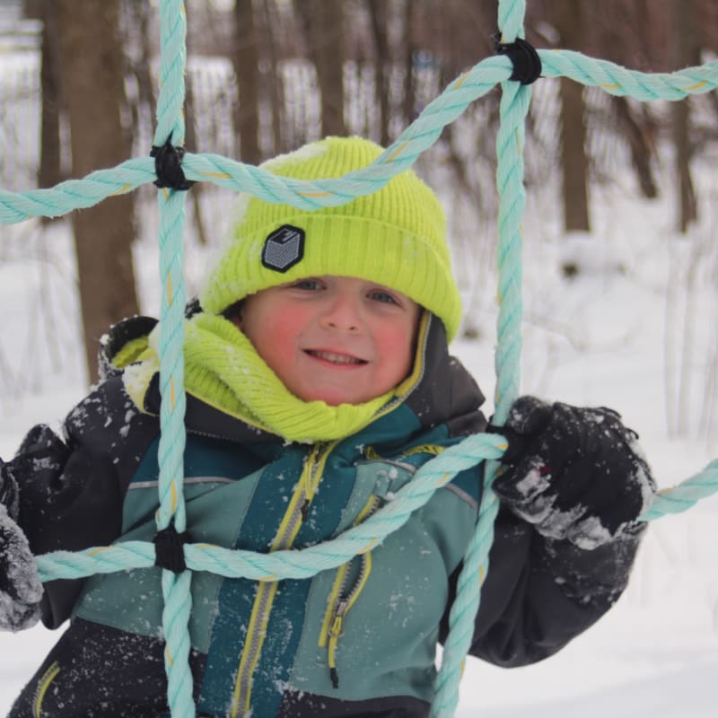 Enfant dans un module de jeux extérieur en hiver.