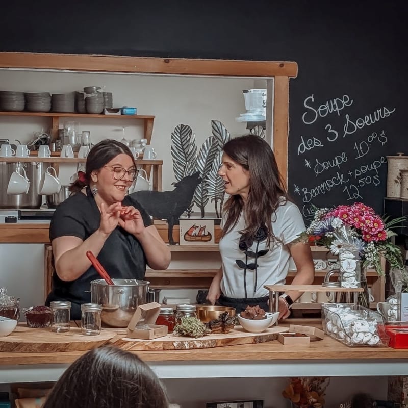 Deux femmes debout derrière un îlot dans une pâtisserie.