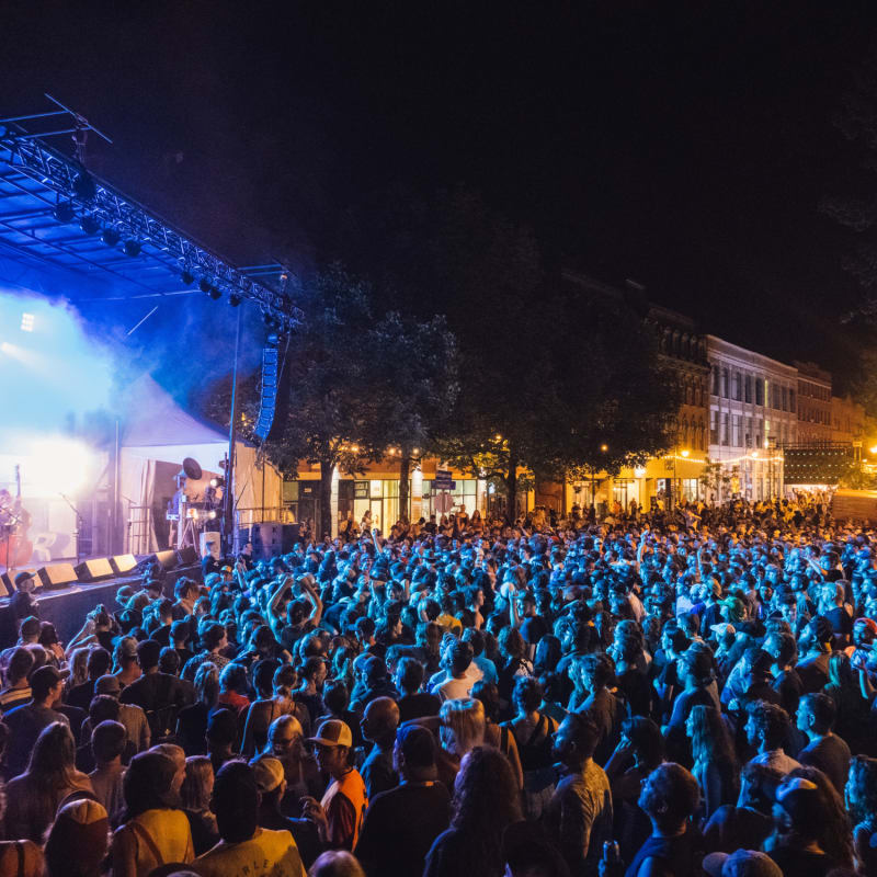 A crowd gathers in the evening in front of an outdoor stage at the Sherblues Festival.